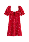 Rotes Kleid mit kurzen puffärmel, quadratischem Ausschnitt und Bindeband vorne. Mit weißen Punkten bedeckt, aus glattem Stoff gefertigt.