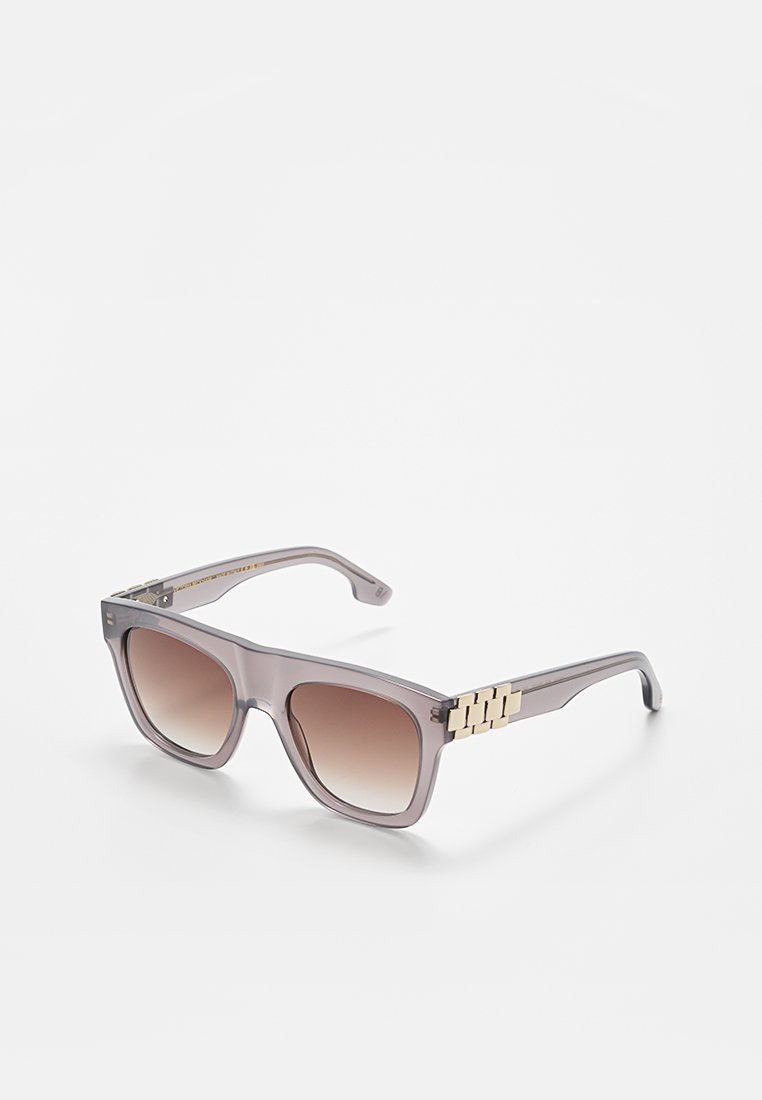 Quadratische Sonnenbrille mit einem transparenten grauen Rahmen, bräunlichen Verlaufsgläsern und goldfarbenen Metallelementen an den Schläfen. Flaches Design, glatte Textur.