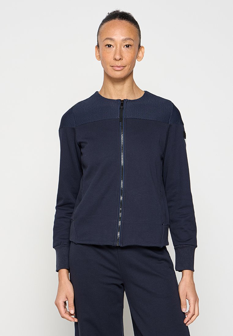 Navy Zip-Jacke mit strukturiertem Schulterpanel, aus weichem Stoff gefertigt. Verfügt über einen hohen Kragen und seitliche Taschen, entworfen für eine figurbetonte Passform.