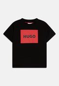 Schwarzes Baumwoll-T-Shirt mit einem roten rechteckigen Logo, auf dem "HUGO" in fetten schwarzen Buchstaben steht. Kurze Ärmel und Rundhalsausschnitt.