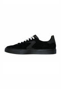 Schwarze Wildleder-Sneaker mit einem glatten, schwarzen Lederakzent, weißen Schnürsenkeln und einer strukturierten, schwarzen Gummisohle. Verfügt über ein elegantes, niedriges Design.