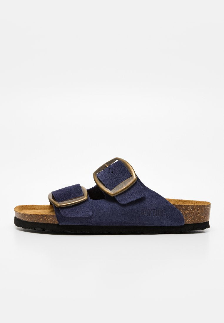 Marineblaue Wildleder-Sandale mit zwei verstellbaren bronzefarbenen Schnallen, Kork-Fußbett, schwarzer Sohle und offenem Zeh-Design.