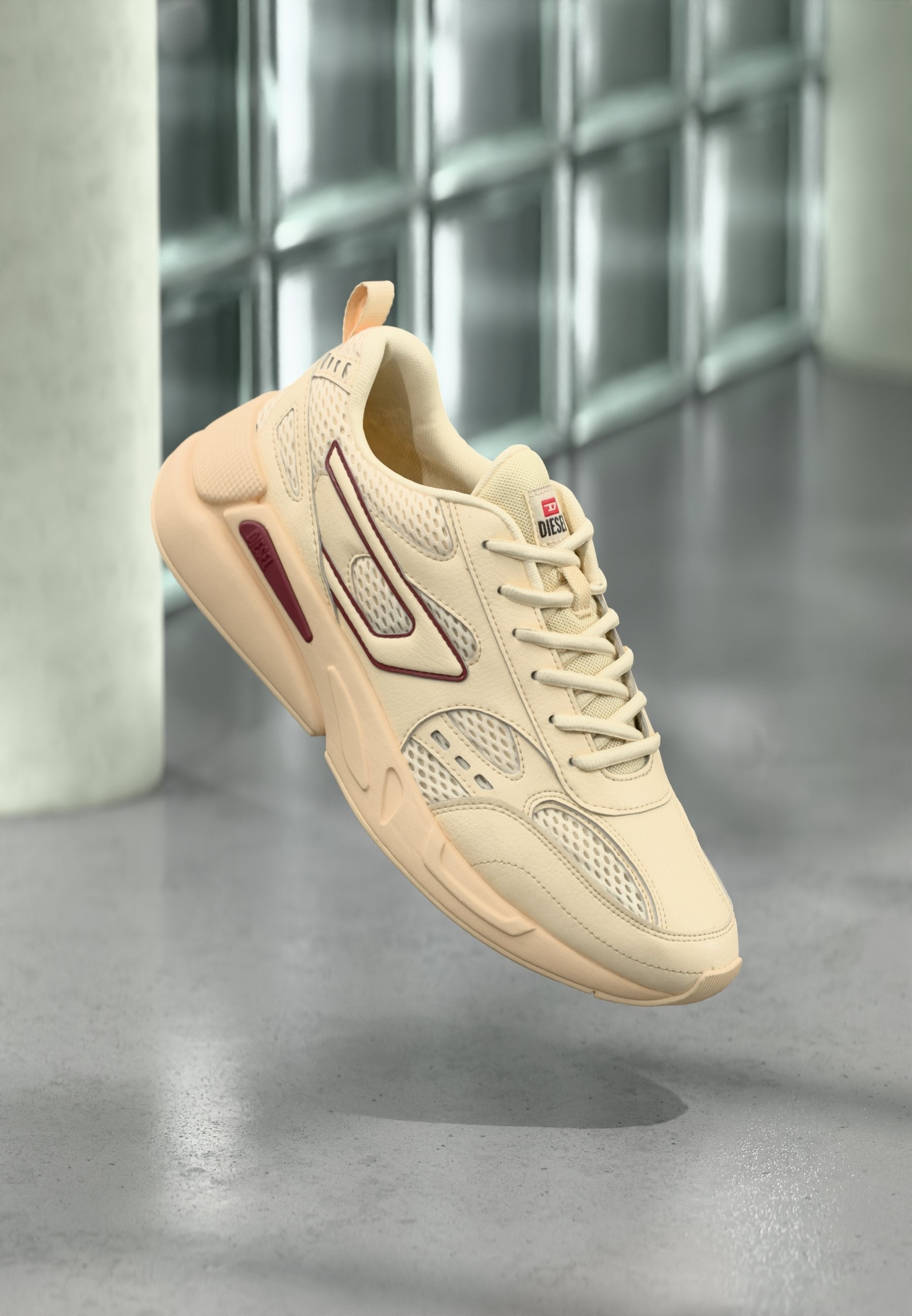 Beiger Sportschuh mit Mesh-Einsätzen und Gummiapplikationen. Verfügt über eine abgerundete Zehenpartie, Schnürsenkel und ein Markenetikett auf der Zunge.