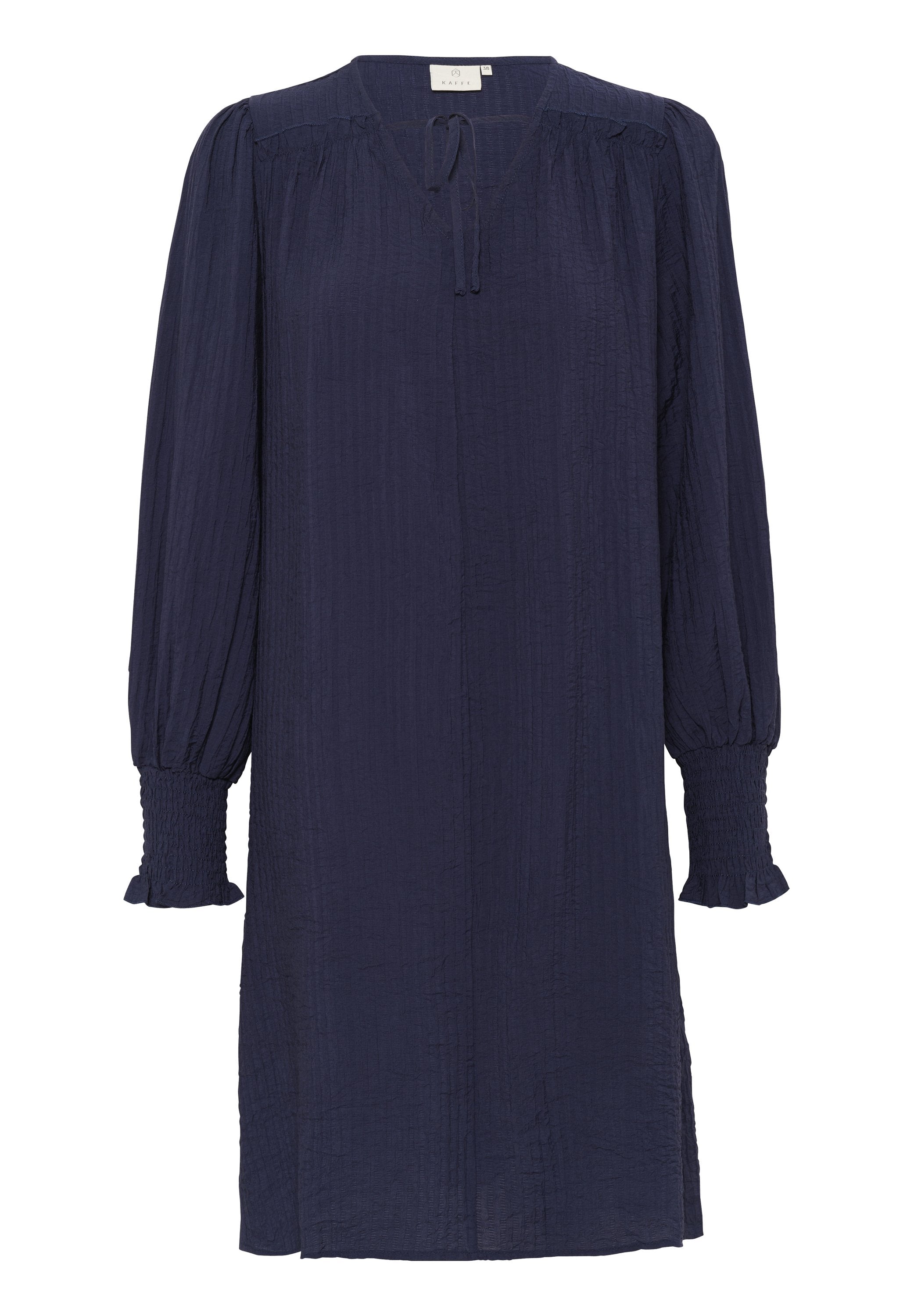 Marineblaues Kleid mit langen, luftigen Ärmeln und gesmokten Manschetten. Verfügt über einen V-Ausschnitt und eine Bindeschleife am Ausschnitt. Hergestellt aus strukturiertem Stoff.