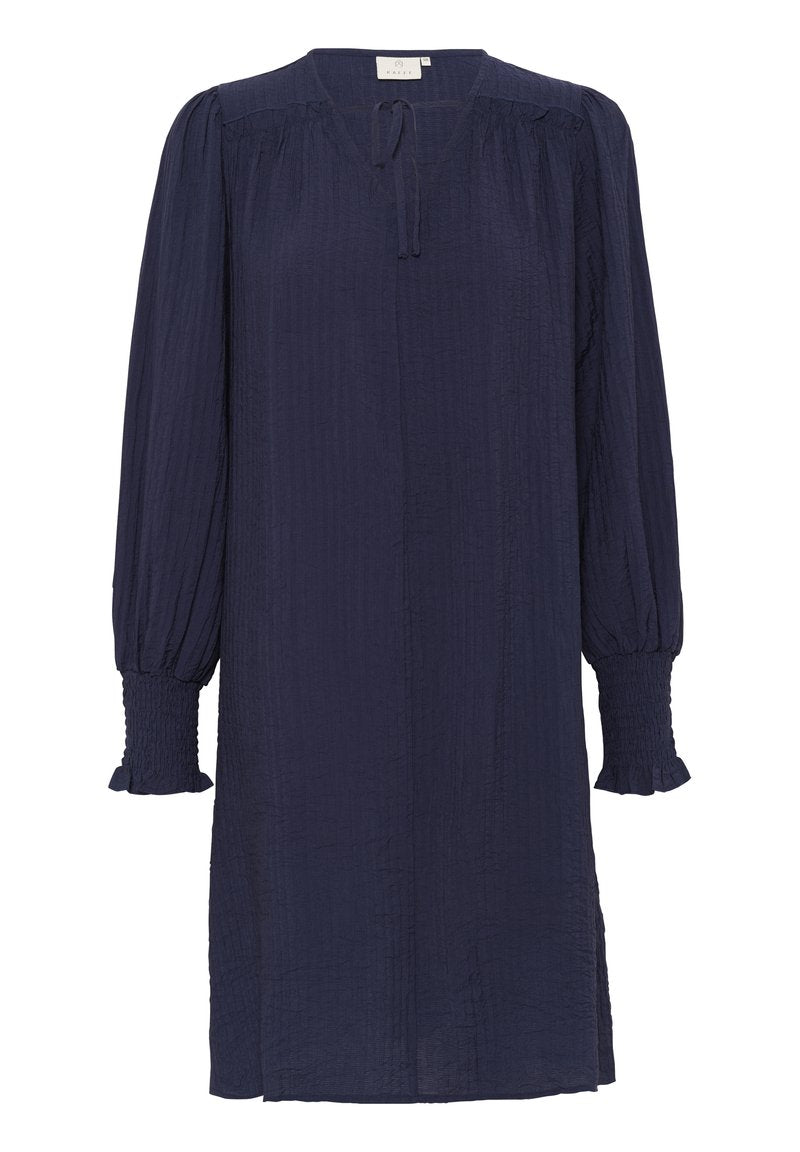 Marineblaues Kleid mit langen, luftigen Ärmeln und gesmokten Manschetten. Verfügt über einen V-Ausschnitt und eine Bindeschleife am Ausschnitt. Hergestellt aus strukturiertem Stoff.