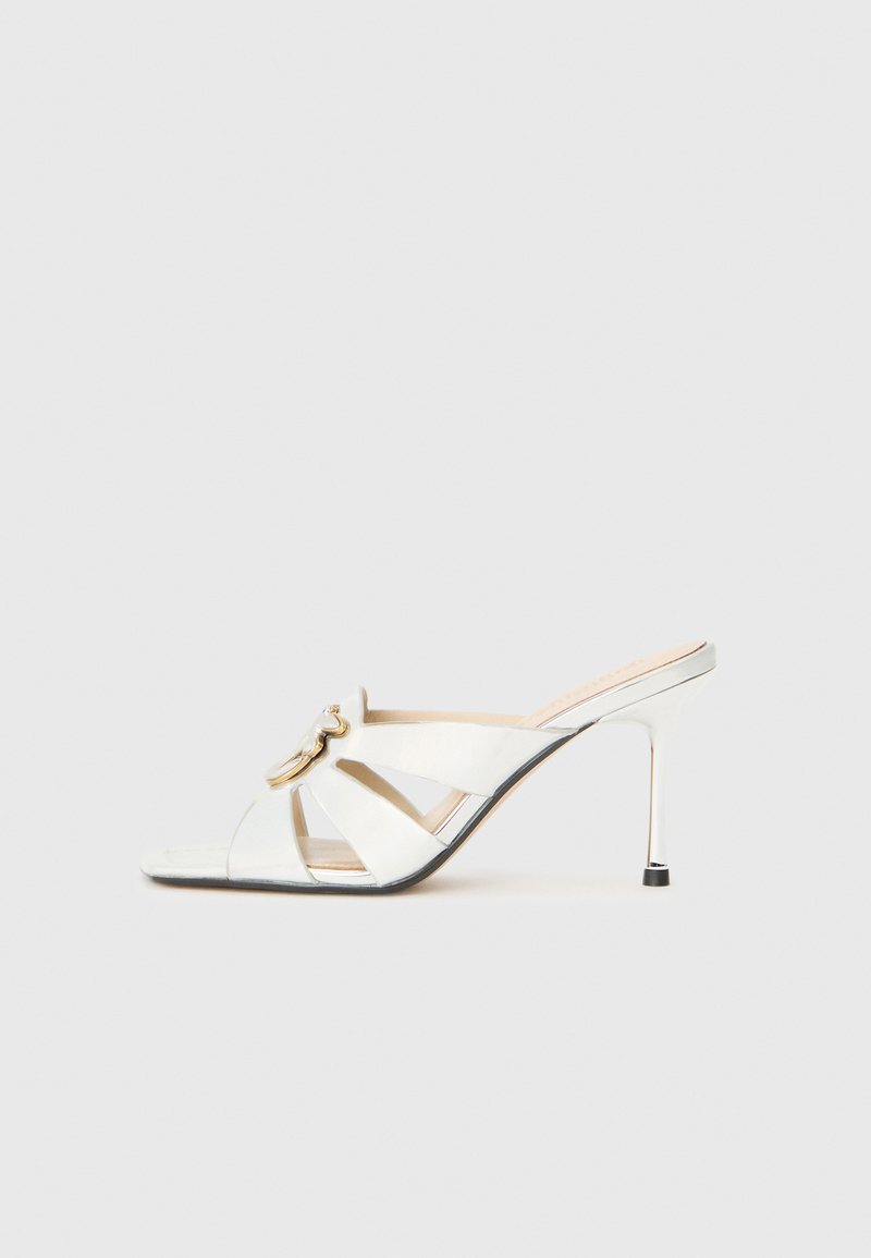 Weißer hochhackiger Sandale mit offenem Zeh, schrägen Riemen, goldenen Akzenten und glänzendem Finish; schlanker, metallischer Stiletto-Absatz.