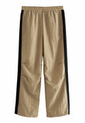 Beige Hosen mit schwarzen Seitenstreifen, aus leichtem Stoff. Mit elastischem Bund und lockerer Passform. Enthält Seitentaschen.