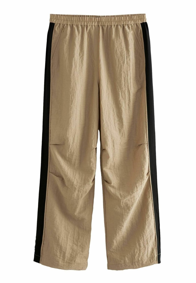 Beige Hosen mit schwarzen Seitenstreifen, aus leichtem Stoff. Mit elastischem Bund und lockerer Passform. Enthält Seitentaschen.