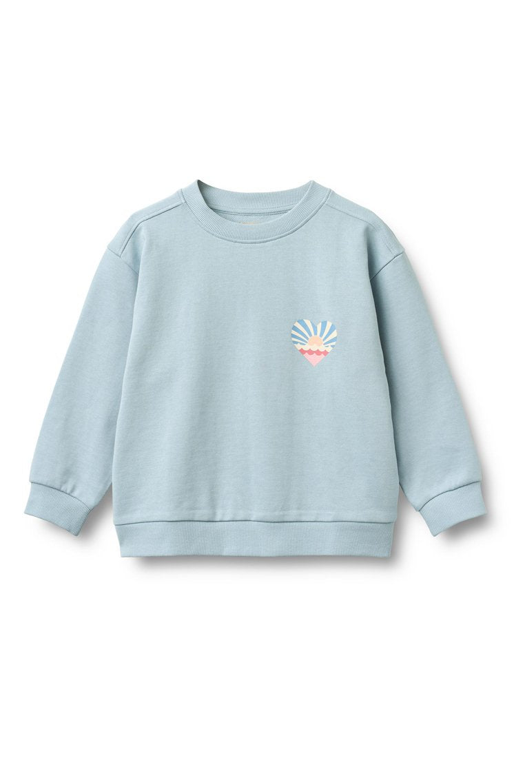 Hellblaues Sweatshirt mit langen Ärmeln, Rundhalsausschnitt und gerippten Bündchen. Zeigt eine herzförmige Grafik mit Sonnen- und Wellenmotiv.