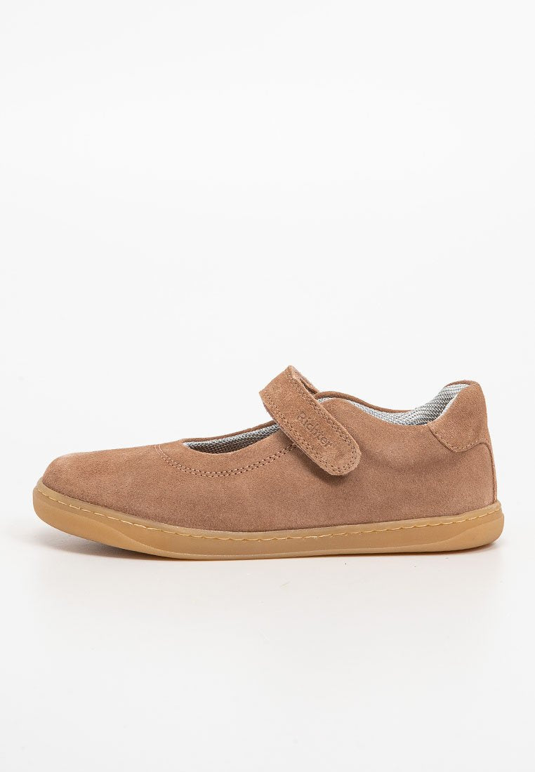 Braune Wildleder-Mary-Jane-Schuhe mit verstellbarem Klettverschluss und beiger Gummisohle, seitlich auf weißem Hintergrund abgebildet.