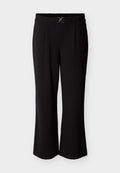 Schwarze Hose mit lockerem Schnitt, ausgestattet mit einem flachen Bund und einem goldfarbenen Akzent vorne. Glatter Stoff mit Falten.