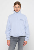 Helle blaue Zip-Up-Sweatjacke aus weichem Stoff. Sie verfügt über einen hohen Kragen, einen elastischen Saum und ein kleines gesticktes Logo auf der Brust.