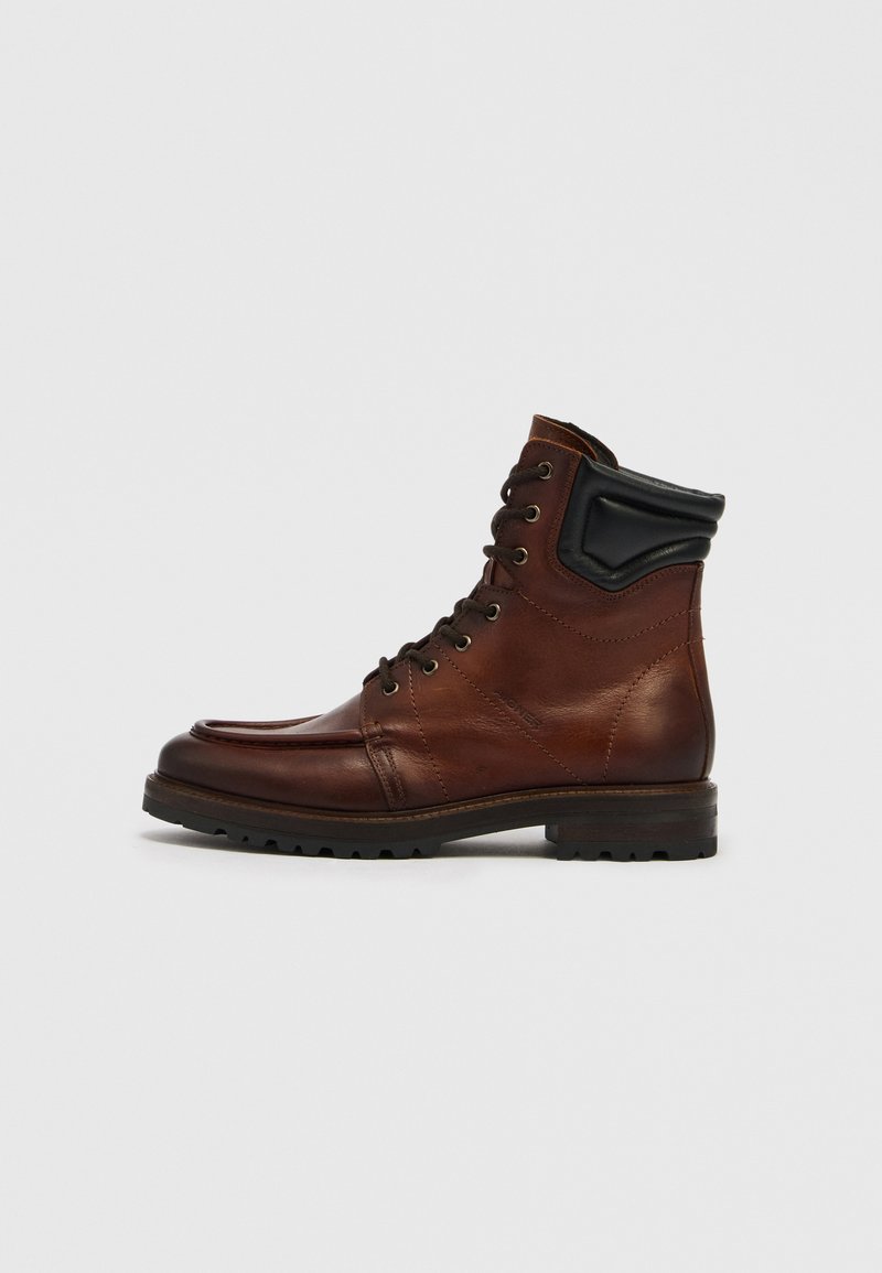 Brauner Leder-Stiefelette mit runder Spitze, Schnürdesign und schwarzen Lederakzenten. Profilsohle für besseren Halt.