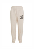 Beige Baumwoll-Sweatpants mit einem elastischen Bund, schmal zulaufenden Bündchen und schwarzem Text, der auf dem linken Bein "The Future Surf Society" liest.