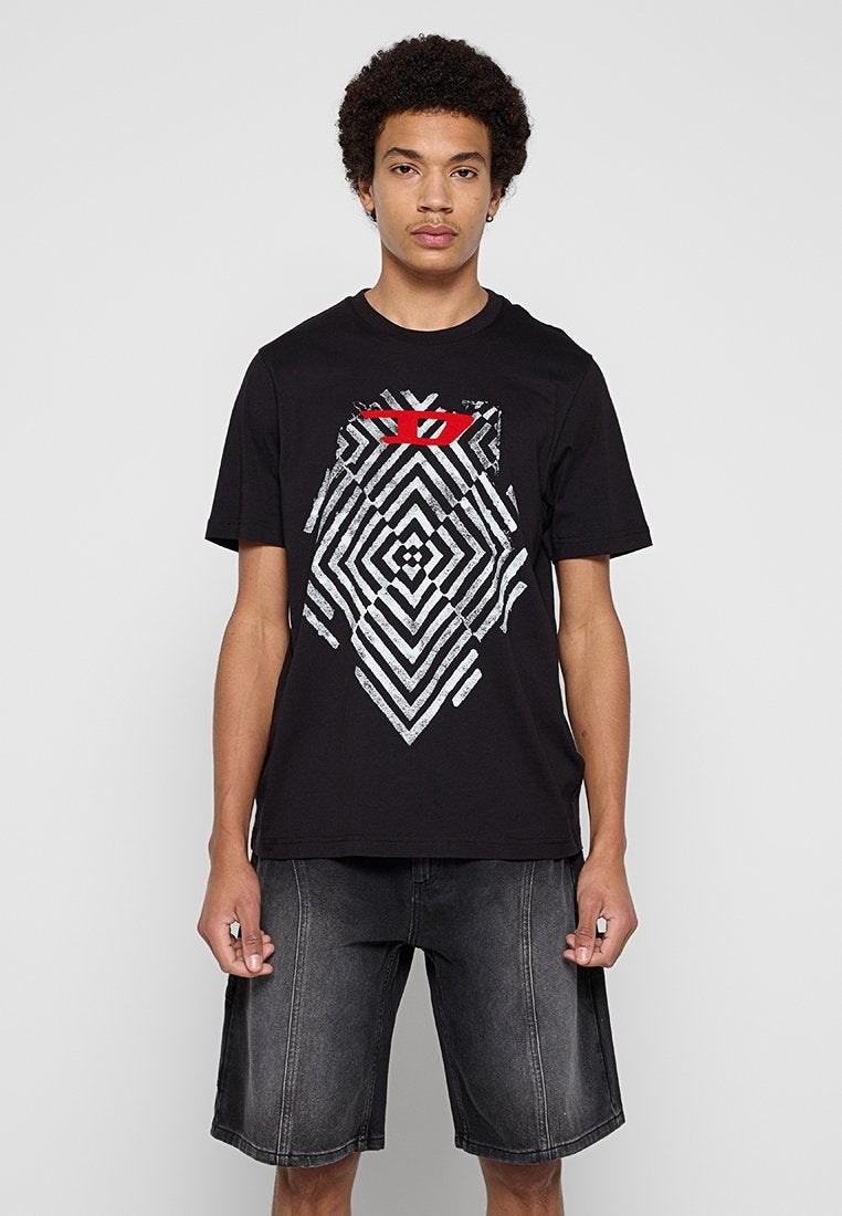 Schwarzes Baumwoll-T-Shirt mit einem geometrischen silbernen und roten Grafikelement auf der Vorderseite. Kombiniert mit dunkelgrauen Denim-Shorts.