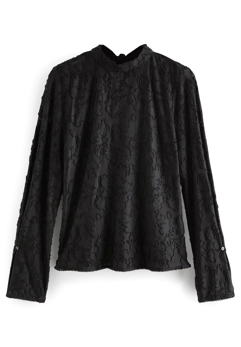 Schwarze Bluse mit langen Ärmeln aus strukturiertem Stoff. Sie hat einen hohen Kragen, einen gewellten Saum und geknöpfte Manschetten mit dezentenDesignmustern.