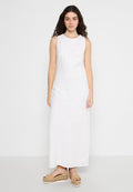 Weißes ärmelloses Maxikleid aus strukturiertem Stoff, mit einem taillierten Oberteil und einem asymmetrischen Saum. Kombiniert mit Plateausandalen.