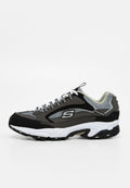 Grauer und schwarzer Sportschuh mit weißen Schnürsenkeln und Sohle, Netzpaneelen und „S“-Logo an der Seite, von der Außenseite gesehen.