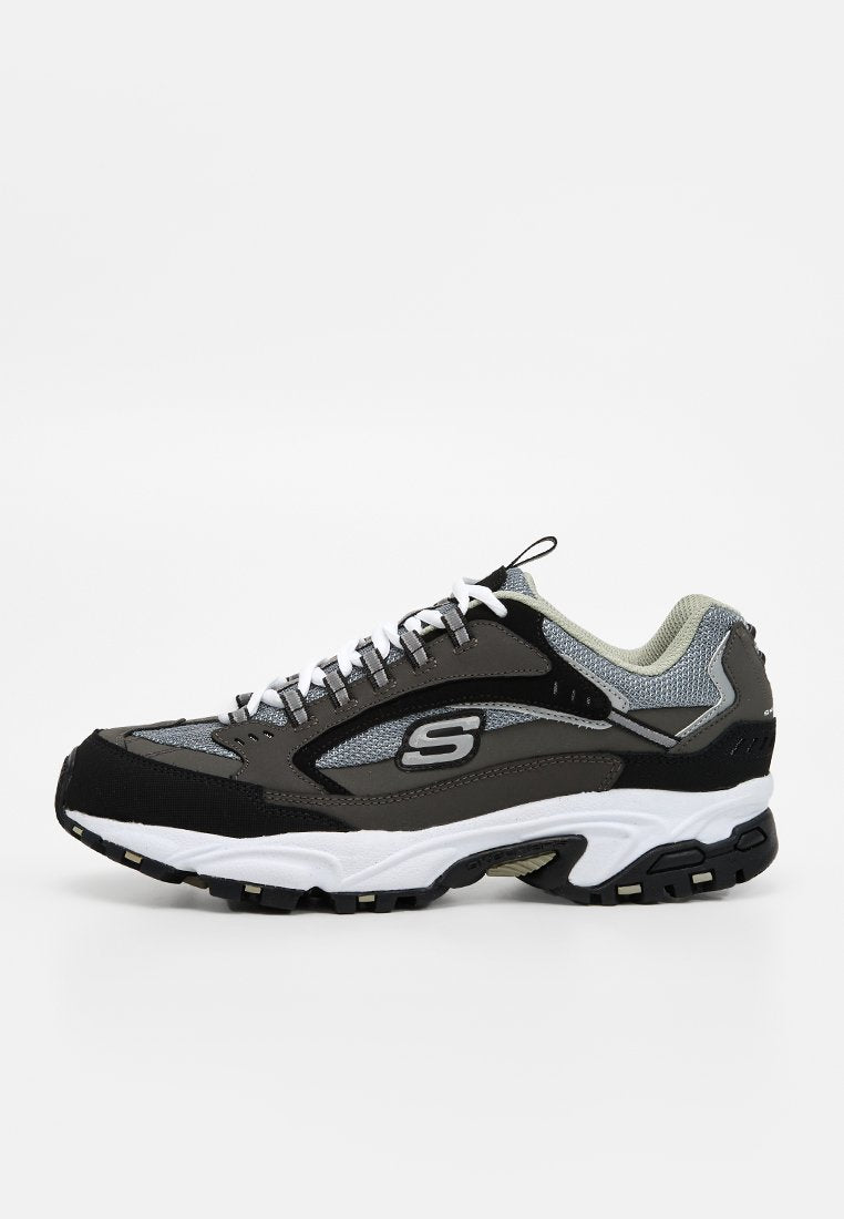 Grauer und schwarzer Sportschuh mit weißen Schnürsenkeln und Sohle, Netzpaneelen und „S“-Logo an der Seite, von der Außenseite gesehen.