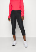 Schwarze, gekürzte Leggings aus glattem, dehnbarem Stoff. Kombiniert mit einem lebhaften, pinkfarbenen, strukturierten Langarmshirt und weißen Sportschuhen.