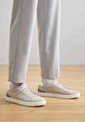 Hellebeige Sneaker mit einem Obermaterial aus Wildleder, kontrastierenden dunklen Akzenten und einer strukturierten Gummisohle. Ausgestattet mit grauen Schnürsenkeln und einem Low-Top-Design.