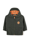 Grüne Jacke mit einem orangen Netzfutter, Reißverschluss, elastischen Bündchen und einem Logo auf der Brust. Mit Fronttaschen.