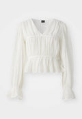 Weiße Bluse mit langen Ärmeln und V-Ausschnitt, strukturiertem Stoff, gerafftem Oberteil und einem Peplum-Saum. Ausgestellte Manschetten bieten zusätzliche Details.