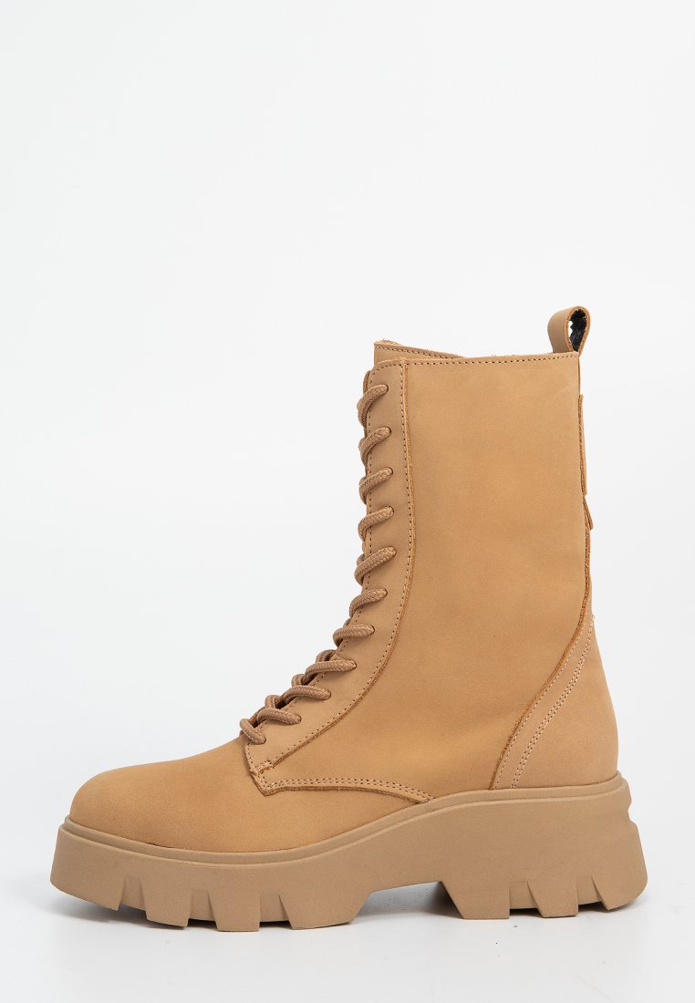 Beige Schnürkampfstiefel mit dicker Profilsohle und Ziehhilfe, seitlich auf weißem Hintergrund dargestellt.