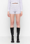 Lila Shorts mit einem strukturierten Muster, kombiniert mit knielangen schwarzen Lederstiefeln. Die Shorts haben einen elastischen Bund und eine figurbetonte Passform.
