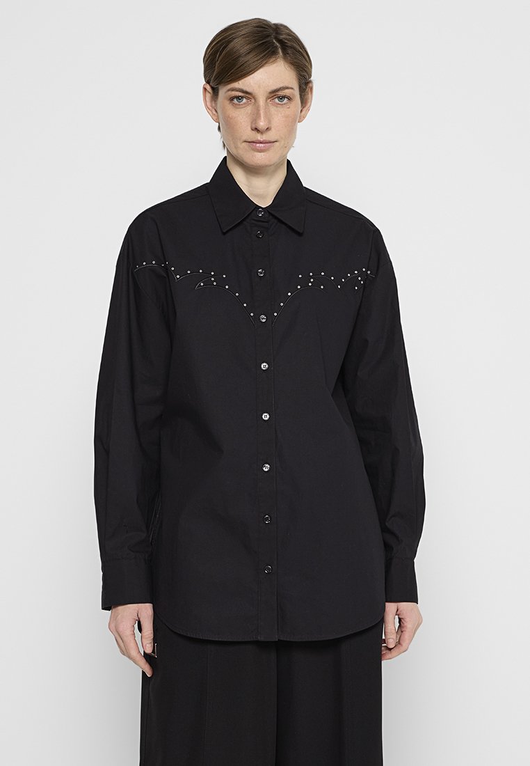 Schwarze Baumwollhemd mit Knopfleiste, das ein markantes Nieten-Design auf der Brust und lange Ärmel aufweist. Minimalistischer Stil mit klassischem Kragen.