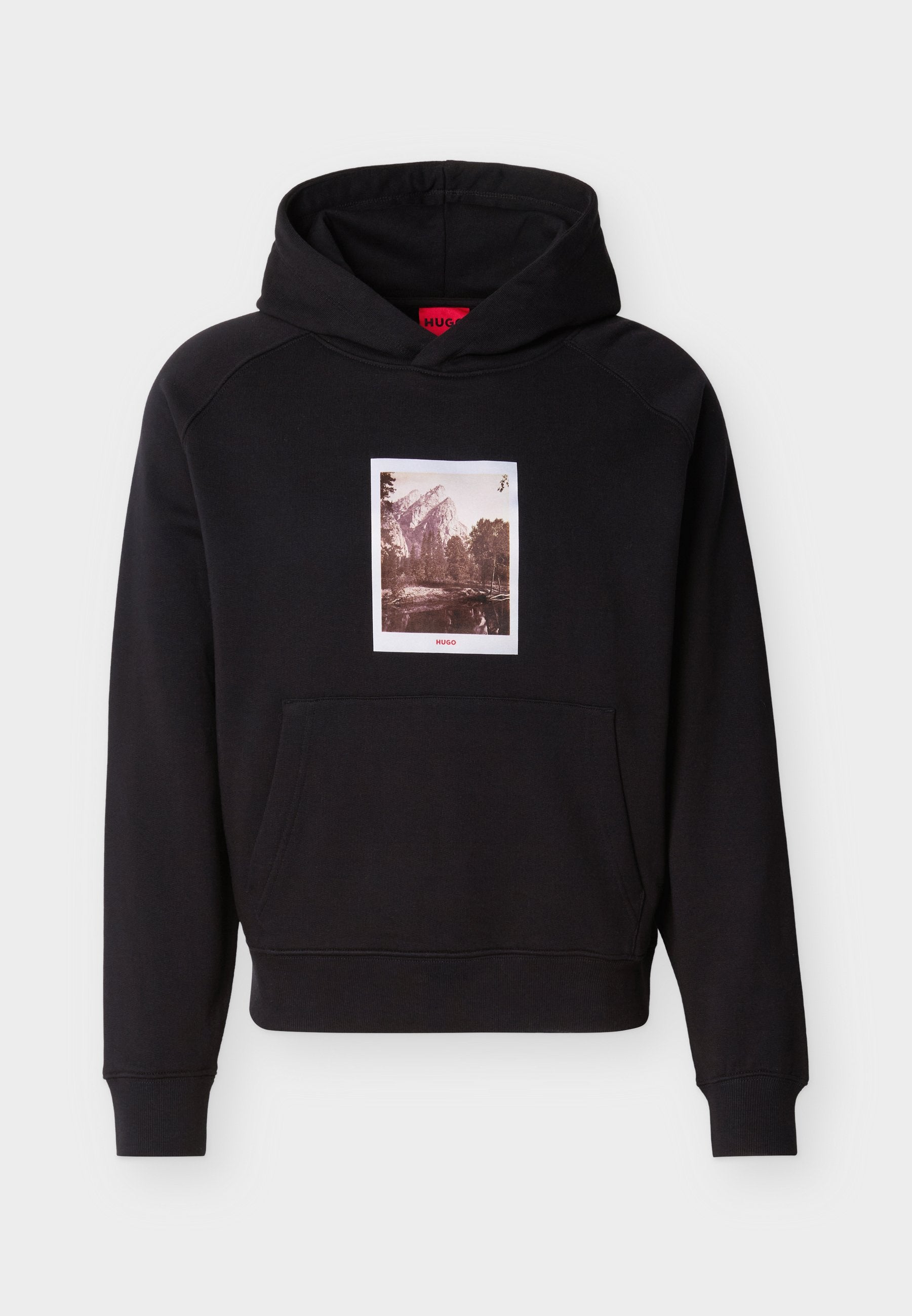 Schwarzer Kapuzenpullover mit Fronttasche und einem Sepia-Berg- und Baumgrafik zentriert über der Tasche mit rotem "HUGO"-Schriftzug.