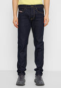 Dunkelblaue Jeans mit gelben Nähten, geradem Schnitt, vorderen Taschen und einem kleinen Etikett an einer Tasche. Getragen mit grauen Schuhen.