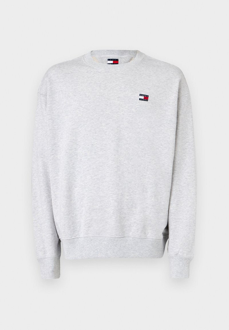 Helles graues Langarm-Sweatshirt mit gerippten Bündchen und Saum, ausgestattet mit einem kleinen Tommy Jeans Logo-Patch auf der Brust.