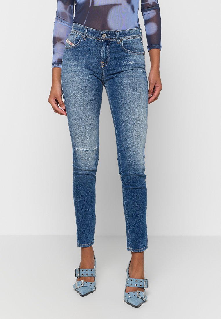 Schlanke blaue Jeans aus Denim, mit ausgefransten Details und höherer Taille. Kombiniert mit hellblauen spitzen Absätzen.