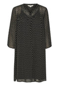 Schwarzes, durchsichtiges Kleid mit weißen rautenförmigen Mustern; verfügt über einen runden Ausschnitt, eine durchgehende Knopfleiste und Dreiviertelärmel.