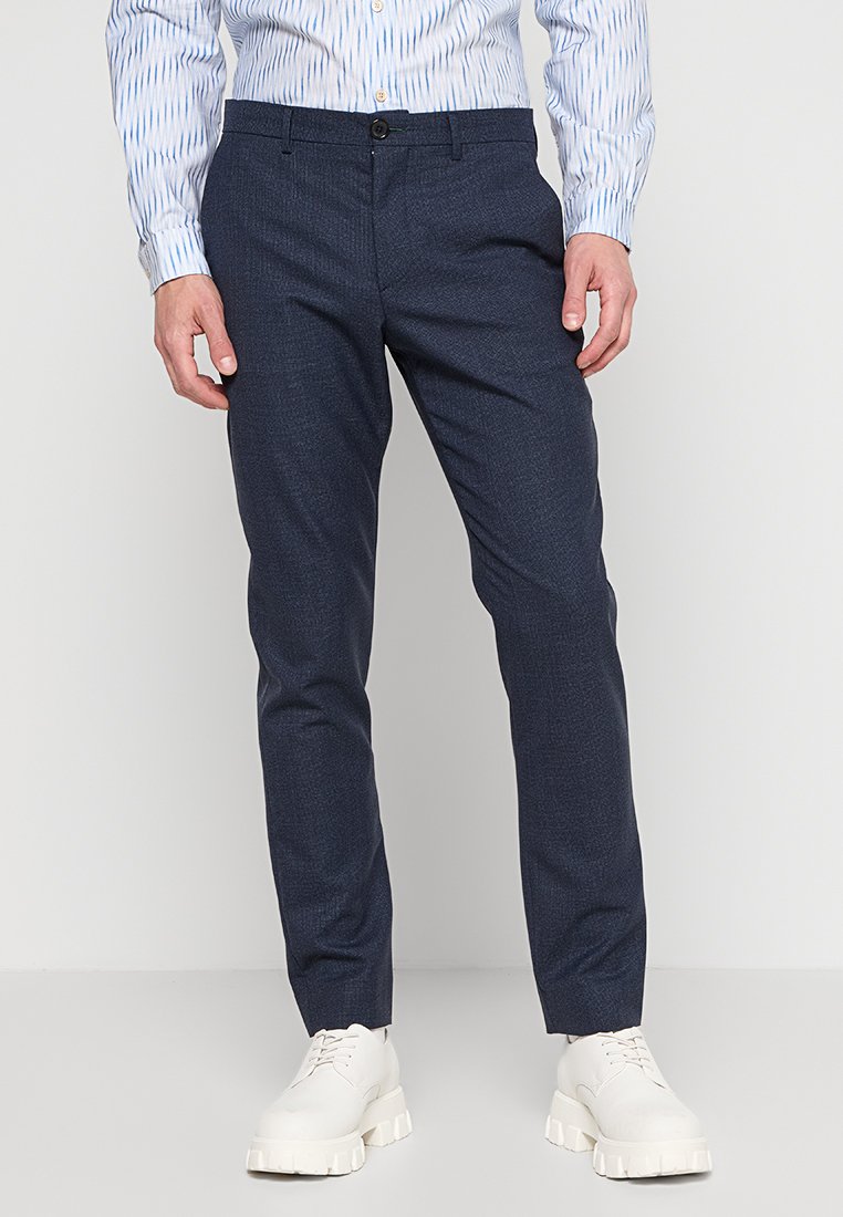 Marineblaue Hose mit dezentem Muster, aus strukturiertem Stoff gefertigt. Verfügt über einen Standardbund und eine schlanke Beinform, kombiniert mit weißen Schuhen.