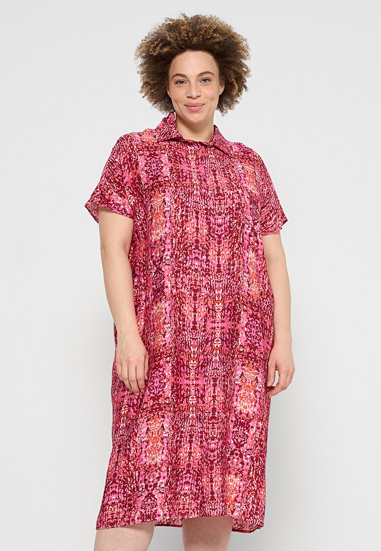 Rosa gemustertes Kleid mit einem kragenförmigen Ausschnitt, kurzen Ärmeln und einem lockeren Schnitt. Es zeigt eine Mischung aus strukturierten Farbtönen in Pink, Orange und Rot.
