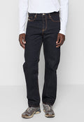 Dunkelblaue Jeans aus Denim mit orangener Naht, gerade geschnitten, fünf Taschen und silbernen Beschlägen, kombiniert mit grauen Turnschuhen.