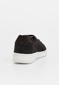 Schwarze Wildleder-Sneaker mit einer weißen Gummisohle, runder Zehenpartie und verstärktem Absatz, mit glatter Textur und einfachem Schnürsystem.