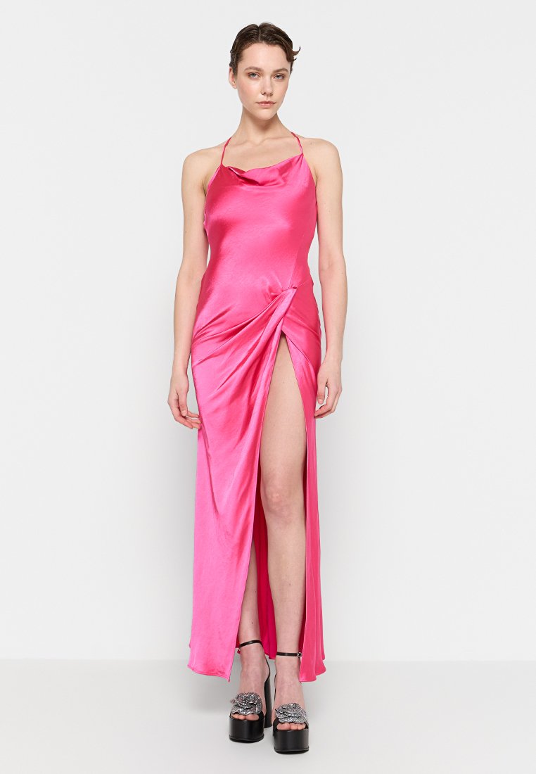 Rosa Satin-Kleid mit einem Cowl-Ausschnitt, einem Oberschenkel-hohen Schlitz und verdrehtem Detail an der Seite, ergänzt durch Plateauschuhe mit dekorativen Riemen.