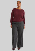Burgunderfarbener Strickpullover mit gerippter Textur, kombiniert mit grauen weit geschnittenen Hosen, die ein dezentes gesprenkeltes Muster aufweisen. Braune Schuhe mit Akzenten.