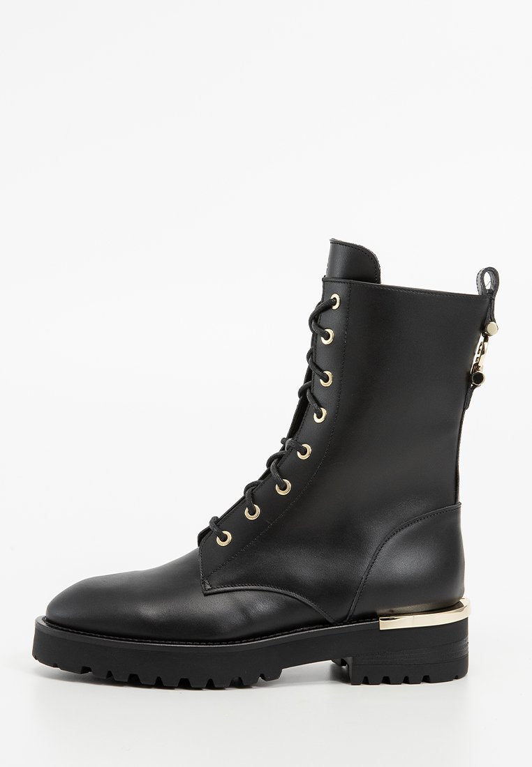 Schwarze Lederkampfstiefel mit goldenen Ösen, schwarzen Schnürsenkeln, einer dicken Profilsohle und einem goldenen metallischen Akzent an der Ferse.