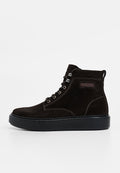Braune Wildleder-Stiefel mit hohem Schaft und schwarzer Gummisohle, ausgestattet mit Metallösen und weißen Ziernähten, entworfen für Komfort und Langlebigkeit.