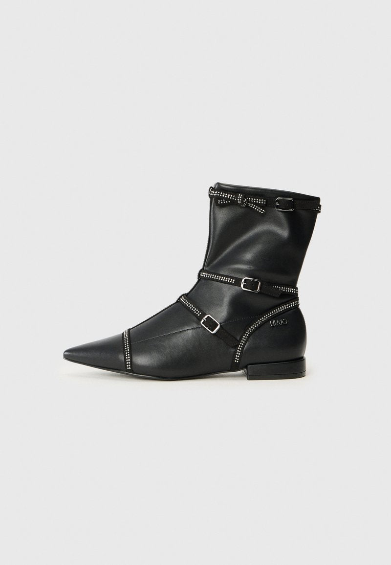 Schwarze Leder-Stiefeletten mit spitzen Zehen, verziert mit dekorativen Riemen, silbernen Akzenten und einem niedrigen Blockabsatz. Glatte Textur mit kontrastierenden Details.