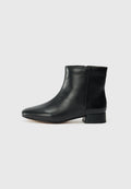 Schwarze Leder-Stiefelette mit spitzem Zehenbereich, niedrigem Blockabsatz, glatter Oberfläche und ohne sichtbare Verschlüsse oder Verzierungen.