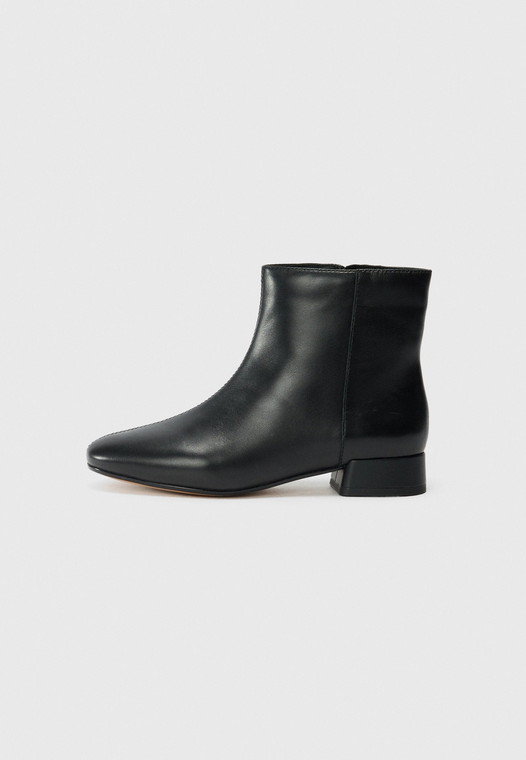 Schwarze Leder-Stiefelette mit spitzem Zehenbereich, niedrigem Blockabsatz, glatter Oberfläche und ohne sichtbare Verschlüsse oder Verzierungen.
