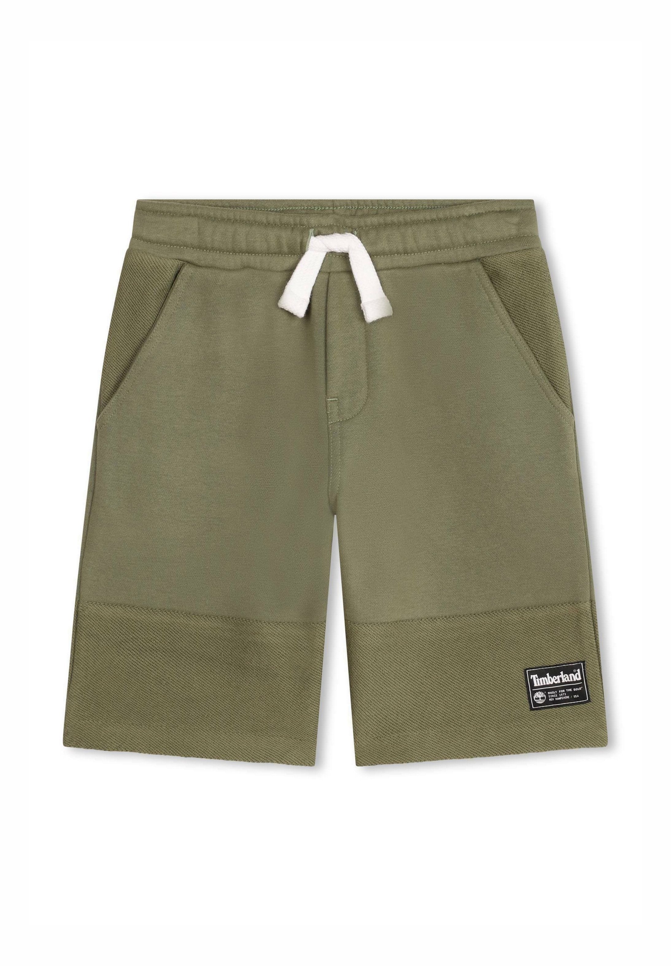 Olivgrüne Shorts aus einem weichen, strukturierten Stoff mit zwei Seitentaschen, elastischem Bund und weißem Kordelzug, versehen mit einem schwarzen Logo-Patch.