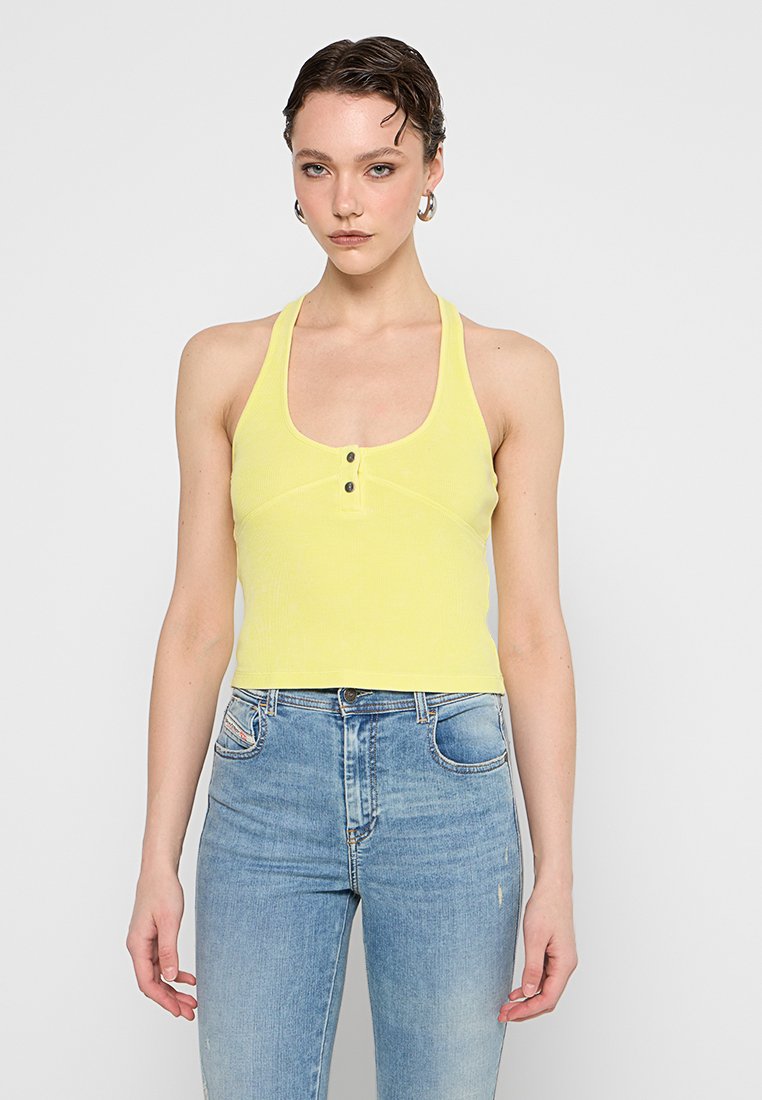 Gelbes, geripptes Tanktop mit rundem Ausschnitt und zwei Knöpfen vorne. Kombiniert mit hellblauen, hoch taillierten Jeans. Glatte Textur, taillierte Passform.