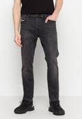 Dunkelgraue Jeans aus Denim mit slim fit, fünf Taschen, dezenten Ausbleichungen und kontrastierenden Nähten. Kombiniert mit schwarzen Sportschuhen.