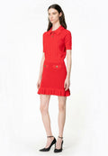 Rotes gestricktes Kleid mit einem kurzärmeligen Polokragen, dekorativen Knöpfen und einem Rüschensaum; kombiniert mit schwarzen High Heels.